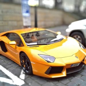 Yellow sports car on a cobblestone street, showcasing sleek design and vibrant color.