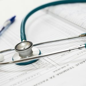 A stethoscope and pen resting on a medical report in a healthcare setting.