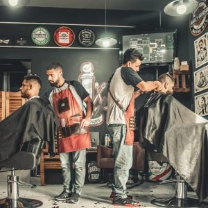 A bustling barbershop with two men getting haircuts, showcasing a vibrant barber environment.