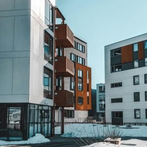 Contemporary apartment buildings with wooden accents in a snowy urban environment.