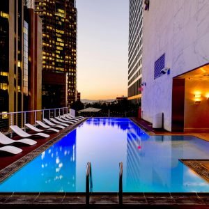 Elegant rooftop pool with cityscape backdrop at sunset, reflecting urban luxury.
