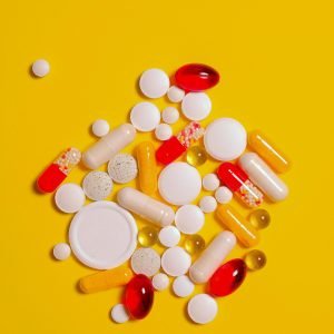A collection of diverse tablets and capsules on a vibrant yellow background, symbolizing healthcare and medication.