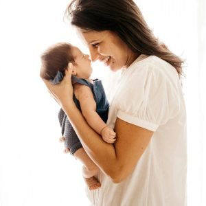 A joyful mother cradles her infant closely, expressing love and happiness.