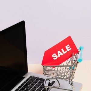 Mini shopping cart with sale tag on laptop for online shopping theme.
