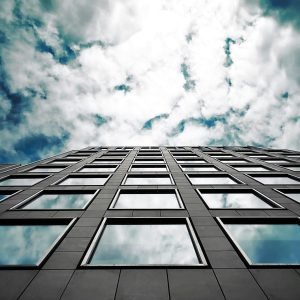 Low angle of a modern skyscraper reflecting clouds in its glass windows with a dramatic sky.