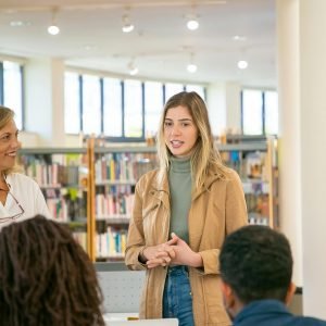 Students and teacher engaged in an active discussion inside a bright university library.