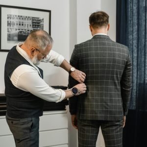 Tailor making precise adjustments to a custom suit in a professional atelier setting.